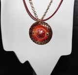 patinaed brass with red orange flower pendant on brick red leather cord and gold chain