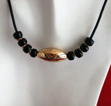 large bronze etched melon bead with black beads on black leather cord