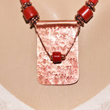 textured red patinaed rectangular copper pendant with red beads on brick red leather cord