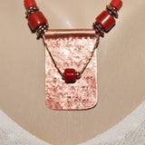 textured red patinaed rectangular copper pendant with red beads on brick red leather cord