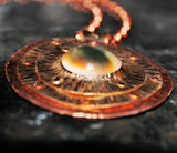 bronze and copper pendant with green operculum cat's eye or eye of shiva
